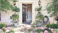  ??  ?? The delicate leaves and flowers of potted plants complement the black door at this entryway designed by Fenimore.