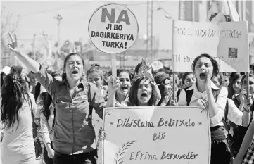  ??  ?? Syrian Kurds hold placards reading “No to the Turkish occupation” as they take part in a protest in the northeaste­rn city of Amude. — AFP photos