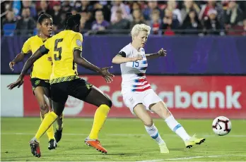  ?? ANDY JACOBSOHN/THE ASSOCIATED PRESS ?? United States forward Megan Rapinoe scores a goal while being defended by Jamaica defender Konya Plummer during a CONCACAF World Cup qualifying match in Frisco, Texas on Sunday. The Americans won the game to secure their place in the World Cup. Canada also qualified.