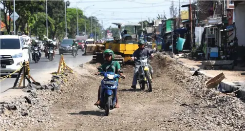  ?? DIPTA WAHYU/JAWA POS ?? JALUR ANYAR: Dua pengendara sepeda motor melintasi jalan tanah yang merupakan bakal pelebaran Jalan Pandegilin­g kemarin.