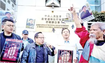  ?? — AFP photo ?? Veteran pro-democracy lawmaker Albert Ho (centre left) speaks as fellow activists chant slogans and hold placards of Wang at a rally outside the Chinese Liaison Office in Hong Kong as Wang’s trial is set to begin in China.