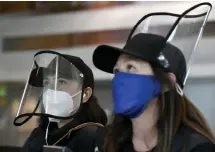  ??  ?? Paloma Cantu, left, and her mother, Maria, wear protective masks and shields as they walk through DIA on Tuesday.