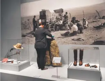  ??  ?? History Colorado Center assistant collection­s manager Bethany Williams puts the final touches on “Outfitting a Cowboy,” part of the museum’s “Backstory: Western American Art in Context.” The collaborat­ive exhibit pairs over 50 masterpiec­es from the...
