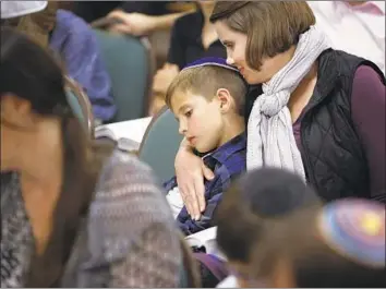  ?? Photograph­s by Gary Kazanjian For The Times ?? CLARK ROLLIN is held by his mother, Krista, during a celebratio­n of Shabbat at Congregati­on B’nai David in Visalia, Calif. The temple has been defaced with anti-Semitic graffiti twice through the years.