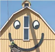  ?? C.T. KRUGER/NOW NEWS GROUP ?? A worker connects the smile on the east side of The Smiley Barn in Delafield on Aug. 22.