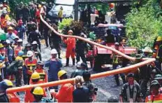  ?? AP ?? Rescuers carry a water pipe to the entrance of a cave complex where the 12 boys and their coach are trapped.