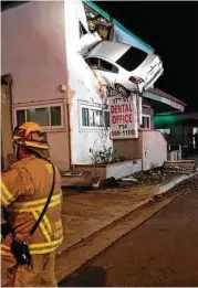  ?? Orange County Fire Authority via New York Times ?? A Nissan Altima hangs from the second story of a dental office building in Santa Ana, Calif., after it went airborne after clipping a median.