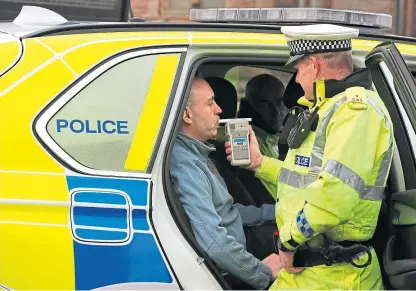  ?? Picture: PA. ?? Road Traffic constable John Parry from Police Scotland demonstrat­es breathalys­er equipment at a drink-drive limit change awareness event at Lockerbie Police Station.