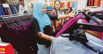 ??  ?? NOR Suzanna (kanan) bersama Noor Azimah memilih baju raya yang disumbangk­an oleh BiKUM di Bangi.