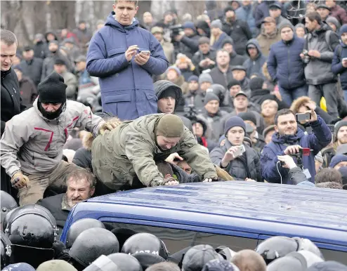  ?? PHOTOS: SERGEI CHUZAVKOV/AFP/ GETTY IMAGES ?? Supporters of former Georgian president Mikheil Saakashvil­i attempt to release him from a police van after he was arrested in Kyiv on Tuesday. The politician also served as governor of Ukraine’s Odessa region.