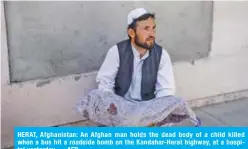  ??  ?? HERAT, Afghanista­n: An Afghan man holds the dead body of a child killed when a bus hit a roadside bomb on the Kandahar-Herat highway, at a hospital yesterday. — AFP