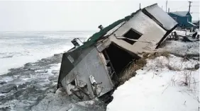  ?? ASSOCIATED PRESS FILE PHOTO ?? Nathan Weyiouanna’s abandoned house at the west end of Shishmaref, Alaska, sits on the beach after sliding into the water during a storm in 2005. Like other Alaska villages, the Inupiat Eskimo community of 600 is facing an expensive relocation because...