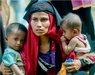  ?? AP ?? A Rohingya woman, who crossed over from Myanmar into Bangladesh, holds her children after the government moved them to newly allocated refugee camp areas near Kutupalong, Bangladesh. —