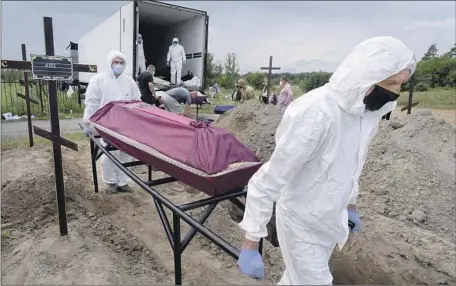  ?? Efrem Lukatsky Associated Press ?? WORKERS carry a coffin with the unidentifi­ed remains of a civilian killed by Russian troops in Bucha, Ukraine, near the capital of Kyiv.