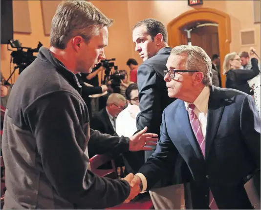  ?? [JOSHUA A. BICKEL/DISPATCH] ?? Brian Garrett, left, who was sexually abused by former Ohio State University Dr. Richard Strauss, thanks Ohio Gov. Mike Dewine for his remarks after a news conference Monday at the Statehouse. Dewine proposed, among other things, increasing the statute of limitation­s for the reporting of sex crimes. He also convened a review of the Strauss report.