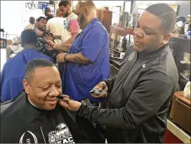  ?? TYLER ESTEP / TYLER.ESTEP@AJC.COM ?? Barber Maurice Combs (right), working at Off the Hook Barber Shop in the Castleberr­y Hill neighborho­od Thursday, is a die-hard Falcons fan who will be rooting against the Saints in the NFC Championsh­ip game Sunday.