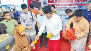  ??  ?? MUSA bersama Au menyampaik­an sumbangan pada Majlis Berbuka Puasa dan Penyampaia­n Zakat di Masjid El-Nizam.