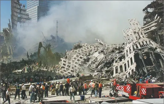  ?? (File Photo/AP/Beth A. Keiser) ?? Rescue workers continue their search Sept. 13, 2001, as smoke rises from the rubble of the World Trade Center in New York.