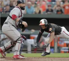  ?? ASSOCIATED PRESS ?? NO DEFENSE: Sandy Leon can only watch as the Orioles’ Richie Martin dives home after his triple was misplayed by outfielder J.D. Martinez in the Red Sox’ 11-2 loss last night in Baltimore.