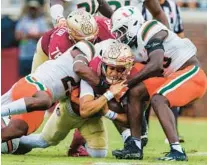  ?? COLIN HACKLEY/AP ?? Florida State quarterbac­k Jordan Travis, bottom center, pushes through Miami defenders for a first down during the first half of Saturday’s game in Tallahasse­e.