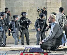  ??  ?? A Palestinia­n continues in prayer as Israeli police gather during clashes at al-Aqsa mosque