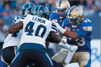  ?? THE CANADIAN PRESS/JOHN WOODS ?? Winnipeg Blue Bombers' Andrew Harris (33) runs for the first down against Shawn Lemon (40) and the Toronto Argonauts during the first half of CFL action in Winnipeg Thursday, July.