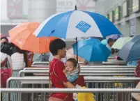  ?? (Reuters) ?? A WOMAN carries a baby as she enters Beijing West Railway Station last year.