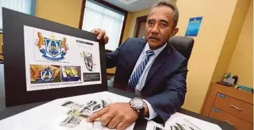  ?? JAMALUDIN
PIC BY MOHD AZREN ?? Johor Baru Central Municipal Council president Adib Azhari Daud showing pictures of the artificial reef and its logo in his Johor office yesterday.