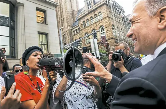  ?? Michael M. Santiago/Post-Gazette ?? Nicky Jo Dawson uses a bullhorn in a confrontat­ion with city Public Safety Director Wendell Hissrich over new guidelines for protesting. Demonstrat­ors had gathered Friday to call on District Attorney Stephen A. Zappala Jr. to make sure jury selection...