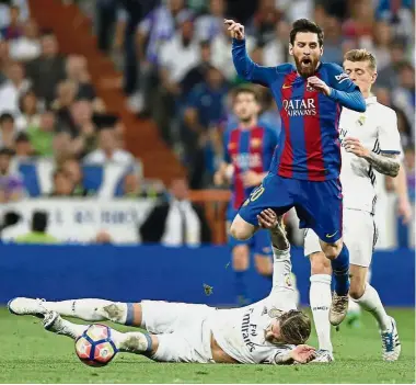  ??  ?? Going down: Barcelona’s Lionel Messi is fouled by Real Madrid’s Sergio Ramos in the La Liga at the Bernabeu on Sunday. — AP