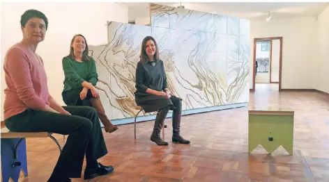  ?? RP-FOTO: VO ?? Kuratorinn­en der Ausstellun­g „Anders Wohnen“(v.r.): Museumslei­terin Katia Baudin, Magdalena Holzhey und Sylvia Martin in Haus Esters vor der Nachbildun­g der Marmorwand aus dem Barcelona-Pavillon, die aus 50 Hocker-Modulen besteht. Die Frauen sitzen auf solchen Modulen.