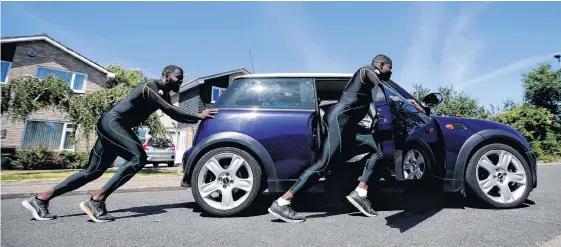  ?? REUTERS • PAUL CHILDS ?? Jamaica Bobsleigh team members Shanwayne Stephens and Nimroy Turgott push a Mini Cooper. They have been pushing the car around the streets of Peterborou­gh as part of their training in Peterborou­gh, Britain.