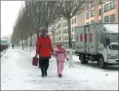  ?? YU CHANGJUN / FOR CHINA DAILY ?? Residents stroll on a frozen street in Yakeshi, Inner Mongolia autonomous region, on Tuesday, wearing thick clothes and masks.