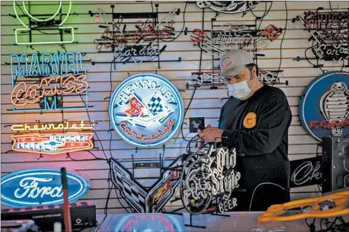  ?? BRIAN CASSELLA/CHICAGO TRIBUNE ?? Neon Shop Fishtail owner Thomas Brickler prepares a sign for a customer Thursday in Bucktown.