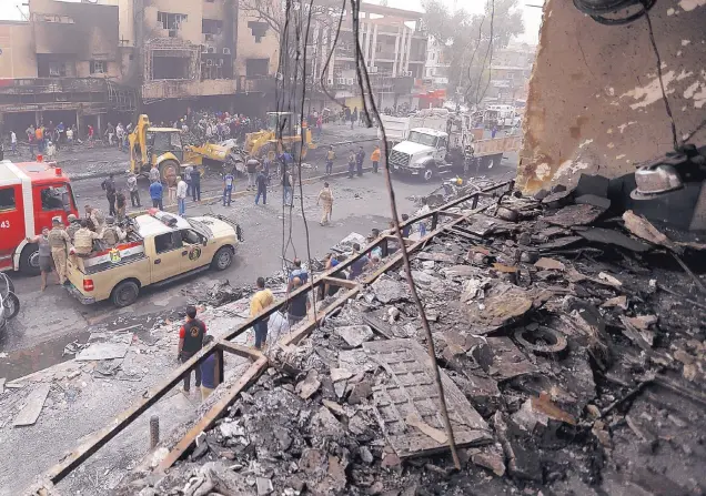  ?? HADI MIZBAN/ASSOCIATED PRESS ?? Iraqi security forces and civilians gather at the site of the deadliest single bombing in 13 years of war. The Baghdad district where the attack by Islamic State militants took place is the city’s most diverse and prosperous area.