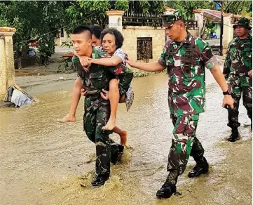  ?? — AFP photo ?? Photo shows soldiers helping residents to evacuate after the flash floods in Sentani.