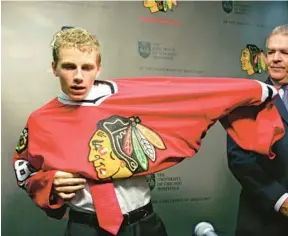  ?? CHARLES CHERNEY/CHICAGO TRIBUNE ?? No. 1 pick Patrick Kane puts on his Blackhawks sweater as he is introduced to the media at the United Center on June 25, 2007.