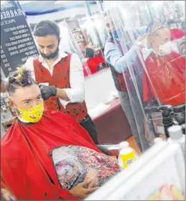  ?? John Minchillo The Associated Press ?? Brian Nieh wears a protective mask as he receives a haircut Monday at Ace of Cuts barbershop in the Manhattan borough of New York. For the first time in three months, New Yorkers were able to dine out, browse in the city’s destinatio­n stores and get haircuts.