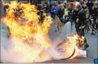  ?? STEPHANE MAHE / REUTERS ?? 2. A bicycle fire is extinguish­ed during clashes with protesters in Paris on Dec 8. 2