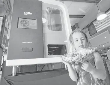  ?? Paul Kuroda photos ?? Isobel More, 5, takes her custom salad from Sally the Salad Robot, a device made by Silicon Valley’s Chowbotics.