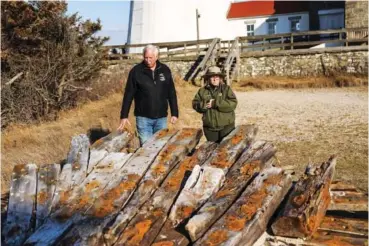  ?? STEVE PFOST/NEWSDAY VIA AP ?? Tony Femminella, executive director of the Fire Island Lighthouse Preservati­on Society, and Betsy DeMaria, museum technician with Fire Island National Seashore, stand Jan. 27 beside a section of the hull of a ship believed to be the SS Savannah, at the Fire Island lighthouse in New York. The SS Savannah wrecked in 1821 off Fire Island.