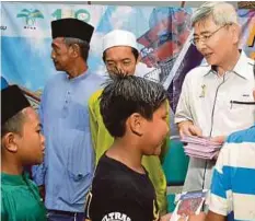  ??  ?? MAH menyampaik­an sumbangan hari raya kepada kanak-kanak di Kampung Selabak, Teluk Intan.