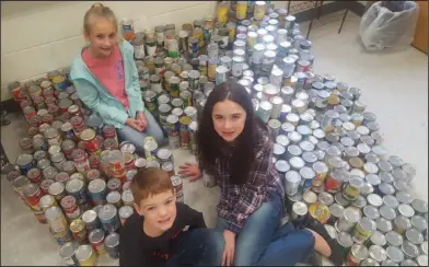  ??  ?? Food: Smackover Elementary Student Council representa­tives Abby Fogle, Judson Wolfe and Madison Ham are pictured with 1007 cans that were collected in a food drive.