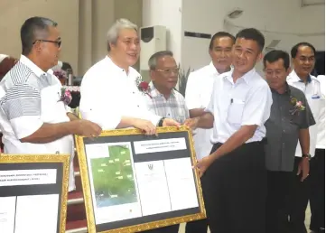  ??  ?? Awang Tengah (second left) presents the land gazette to Tuai Rumah Ijau Ikok, as (from left) Aaron, Gramong, Len Talif, Alexander and Petrus look on.