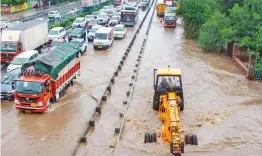  ?? — PTI ?? Commuters wade through the waterlogge­d Delhi-Gurgaon Expressway and service road after heavy rains at Narsinghpu­r in Gurgaon on Wednesday.