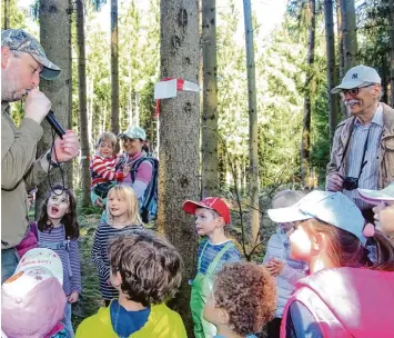  ?? Fotos: Sabine Roth ?? Beim Waldtag macht Jäger Philipp Eisele Tiergeräus­che nach, um Tiere anzulocken. Die Kinder und Hans Holzinger von den Gartenfreu­nden (rechts) sind fasziniert.