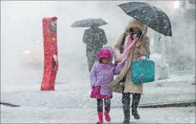  ?? MARY ALTAFFER / ASSOCIATED PRESS ?? Pedestrian­s walk along a street in New York City during the snowstorm on Wednesday. Some parts of the US East Coast saw more than 60 centimeter­s of snow, which made traveling treacherou­s.