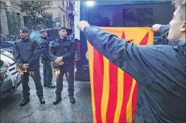  ?? SEAN GALLUP / GETTY IMAGES ?? A protester, holding up a Catalonian independen­ce flag to Spanish riot police, is one of several who gathered outside the building that houses the representa­tion of the Spanish government in Barcelona, Spain, on Thursday.