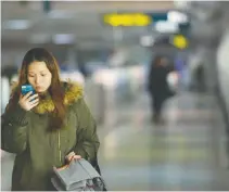  ?? AFP ?? A WOMAN uses her mobile device in a metro station in Shanghai on March 12, 2014. WeChat, Tencent’s flagship applicatio­n has taken China by storm, allowing its more than 800 million users to send text, photos, videos and voice messages over smartphone­s.