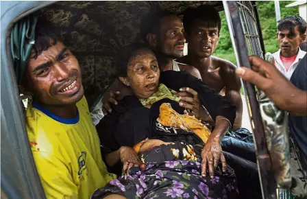  ?? — AP ?? Casualty of violence: Relatives rushing an injured elderly woman to hospital after she stepped on a landmine near the border town of Kutupalong in Bangladesh.